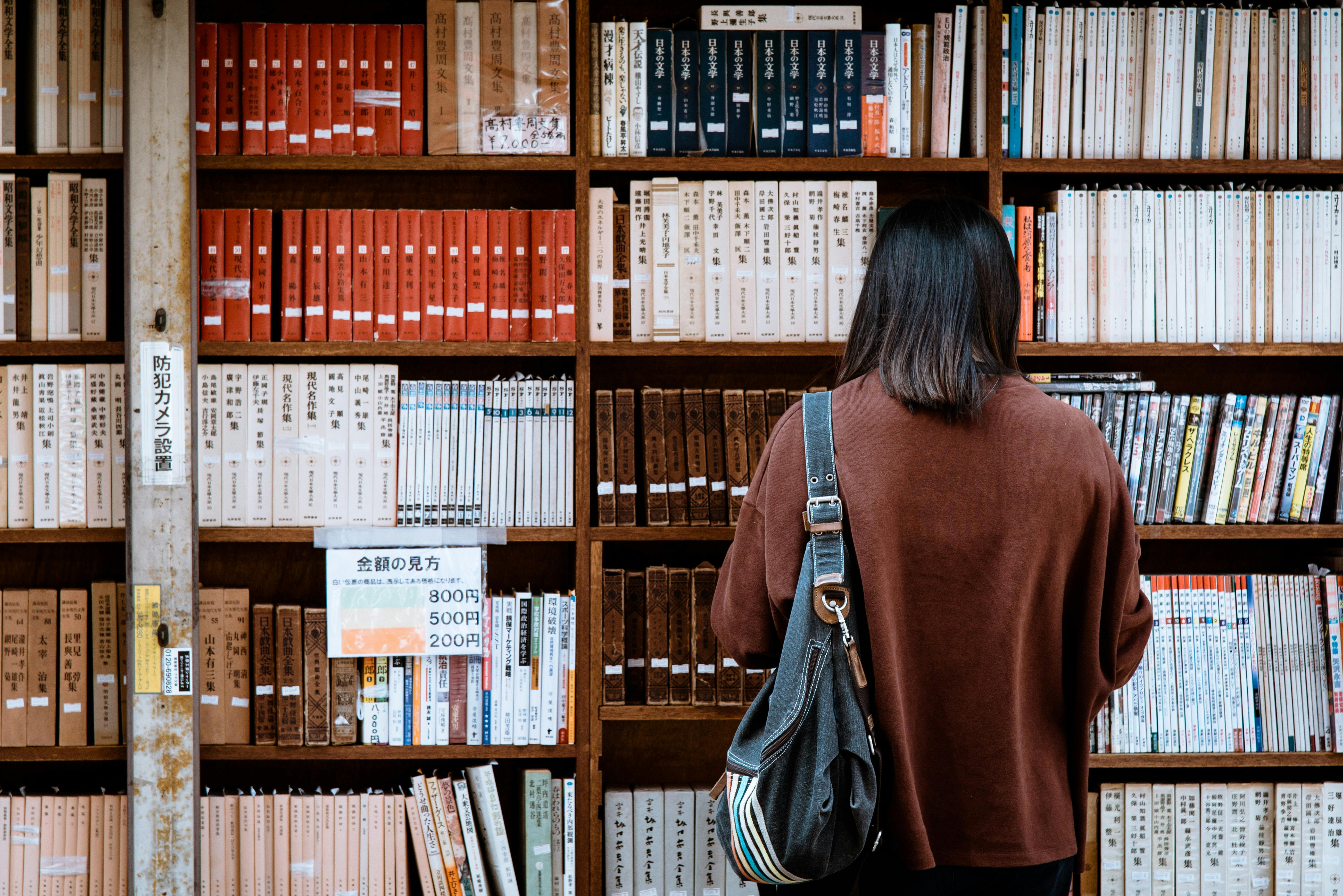A person browsing books in a library, symbolizing curated creativity.